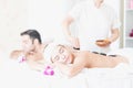 Male and Female massage therapist giving a massage at a spa. Woman having hot stones on her back in spa salon Royalty Free Stock Photo