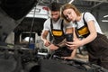 Male and female mechanics repairing engine of automobile