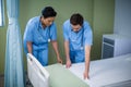 Male and female nurse preparing bed for patient