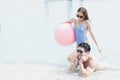 Male and female playing in the pool with a beach ball. Young couple embracing in the pool Royalty Free Stock Photo