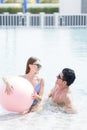 Male and female playing in the pool with a beach ball. Young couple embracing in the pool Royalty Free Stock Photo