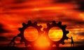 Male and Female Pushing Gears At Sunset Orange sky. Business Persons Collaborate Together to Connect The Cogwheels.