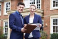 Male And Female Realtor Standing Outside Residential Property