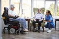 Male And Female Residents Sitting In Chair And Talking With Nurse In Retirement Home Royalty Free Stock Photo