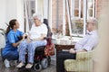 Male And Female Residents Sitting In Chair And Talking With Nurse In Retirement Home Royalty Free Stock Photo