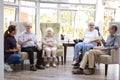 Male And Female Residents Sitting In Chairs And Talking With Carer In Lounge Of Retirement Home Royalty Free Stock Photo