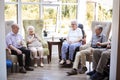 Male And Female Residents Sitting In Chairs And Talking In Lounge Of Retirement Home Royalty Free Stock Photo