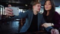 Girlfriend and boyfriend sitting in cafe taking selfie with smartphone.