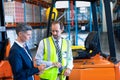 Male and female staff discussing over clipboard near forklift Royalty Free Stock Photo