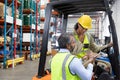 Male and female staff discussing over clipboard in warehouse