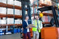 Male and female staff interacting with each other near forklift in warehouse Royalty Free Stock Photo