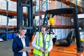 Male and female staff working together near forklift in warehouse Royalty Free Stock Photo