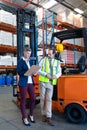 Male and female staff working together near forklift in warehouse Royalty Free Stock Photo