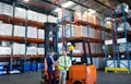 Male and female staff working together near forklift in warehouse Royalty Free Stock Photo