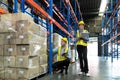 Male and Female Supervisors Hold Digital Tablet is checking the number of items in the warehouse that he is responsible for.