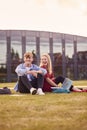 Male And Female University Or College Students Sit On Grass Outdoors On Campus Talking And Laughing Royalty Free Stock Photo