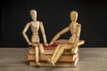 Male and female wooden mannequins sitting on books Royalty Free Stock Photo