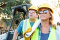 Male and Female Workers With Technical Blueprints at Construction Site