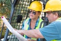 Male and Female Workers With Technical Blueprints Talking at Con