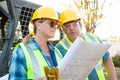 Male and Female Workers With Technical Blueprints Talking