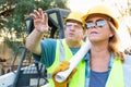 Male and Female Workers With Technical Blueprints Talking at Con