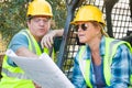 Pointing Male and Female Workers With Technical Blueprints Talking Royalty Free Stock Photo
