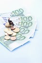 Male figurine sitting on stack of euro coins and notes