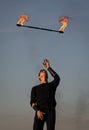 Male fire performer manipulate with flaming baton on blue sky outdoors, man