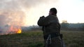 Male fireguard in equipment walking with fire hose on dry grass at countryside. Young fireman in uniform going to