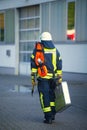 Male fireman walking down a city street carrying a suitcase in his hands