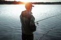 A male fisherman on the lake is standing in the water and fishing for a fishing rod. Fishing hobby vacation concept. Copy space