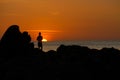 Male fisherman standing on the rocks during sunset