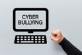 Male fist with a computer icon with cyber bullying written on the screen. Harassment, intimidation and humiliation in cyber space