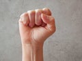 Male fist on gray background. Raised fist as human hand up with protest, victory, strength, power. Counting, aggression, brave