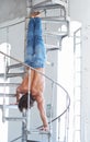 A man in blue jeans upside down on iron ladder. Royalty Free Stock Photo