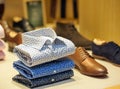 male floral shirts next to leather shoes for sale in showcase of a modern store Royalty Free Stock Photo