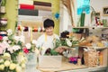 Male florist in flower shop. Man in apron is cutting stems and preparing roses for a bouquet. Owner of the flower shop, doing Royalty Free Stock Photo