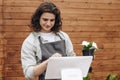 Male florist in flower shop standing and talking to beautiful female client and giving her plant. Portrait of handsome Caucasian Royalty Free Stock Photo