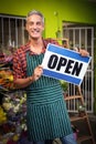 Male florist holding open signboard at flower shop