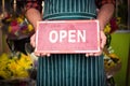 Male florist holding open signboard at his flower shop