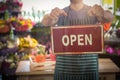 Male florist holding open signboard at his flower shop