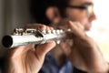 A male flutist playing, indoors.