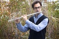 A male flutist playing outdoors.