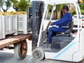 Male forklift driver unloading delivered grapes harvest from truck platform