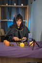 male fortune teller reads tarot cards for predictions, telling customers by providing services via webcam of mobile Royalty Free Stock Photo