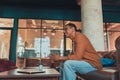 Smiling male freelancer in eyeglasses drinking coffee during break time in coworking Royalty Free Stock Photo