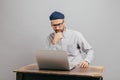 Male freelancer reads news in internet, looks attentively at laptop computer, watches video, sits at old table, wears white shirt Royalty Free Stock Photo