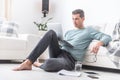 Male freelancer sits barefoot on the living room floor working on a laptop
