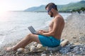 Male freelancer working vacation on a laptop. Summer vacation on the beach