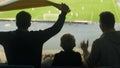 Male friends with child watching football at stadium, adrenaline and emotions